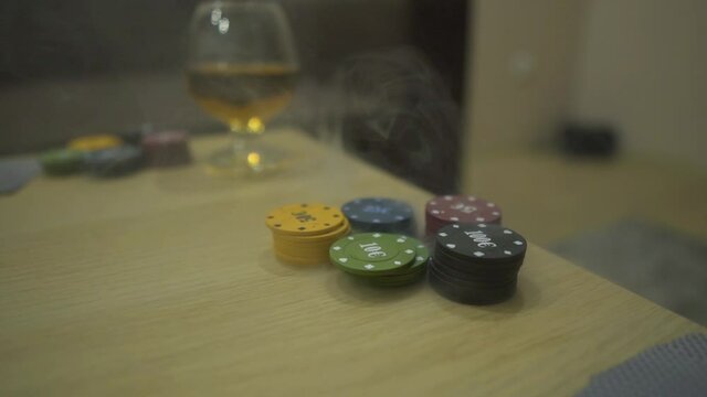 Poker Chips in Smoke and a Glass with Alcohol Drink Stands on the Table. Concept of Playing Poker, Home Entertainment During Quarantine. Smoke Envelopes Poker Chips.