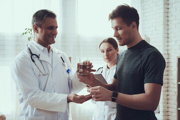 Obraz premium Adult doctor man giving a pill to an athlete. 