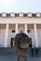 Rear view of student looking at his closed university. Vertical shot. Concept of suspended classes and return to study.