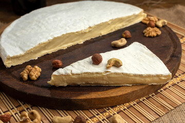 artisan cheeses with dried fruits glass of wine, homemade country bread, bunch of grapes, on wooden board with knife