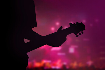 Silhouette of guitar player in concert with purple light
