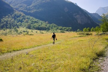 Fototapeta na wymiar An isolated man is walking on an hike trail in a plain under the Sibillini Mountains (Marche, Italy, Europe)