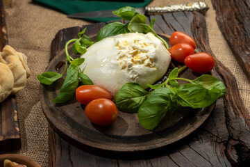 burrata cheese mozzarella mixture of threads and fresh cream on wooden board with cherry tomatoes basil