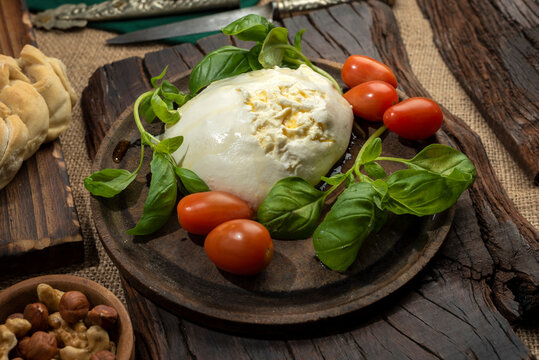 burrata cheese mozzarella mixture of threads and fresh cream on wooden board with cherry tomatoes basil