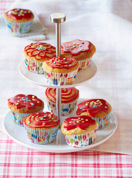 Muffins with red icing and sugar confetti on a cake stand