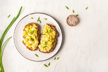 Scrambled Eggs on wholewheat toast. Delicious breakfast or snack on a light background, top view, copy space