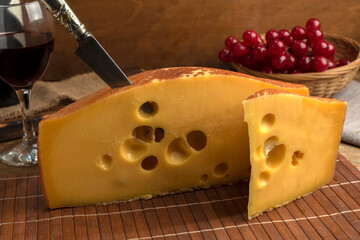 artisan cheeses with dried fruits glass of wine, homemade country bread, bunch of grapes, on wooden board with knife