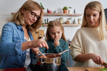 Three generations of women preparing food in the kitchen