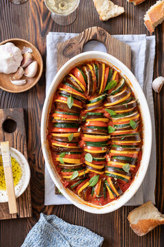 Ratatouille in a baking dish, bread, basil leaves, garlic, herb olive oil