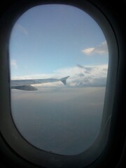 Fototapeta na wymiar ventanilla de avión, cielo, nubes y ala