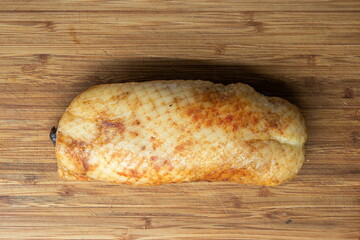 Whole smoked goose breast sat on wooden kitchen board top view skin side up