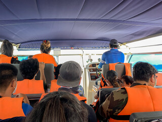 Tourists with life jacket travelling in the sea by speedboat.
