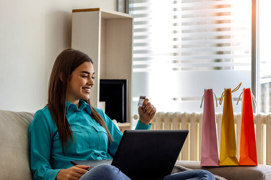 Happy smiling girl using laptop and credit card. Happy woman shopping online with laptop at home. Girl using laptop computer shopping online. Shot of a young woman cheering while using laptop at home