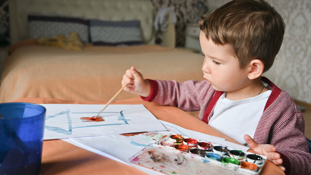Portrait of cute little child drawing at home. Close-up of kids hands painting at home during coronavirus pandemic.