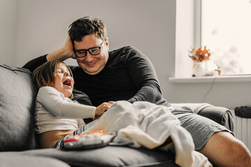 Obraz premium Father with child on the couch. Cozy home activity with child. fatherhood