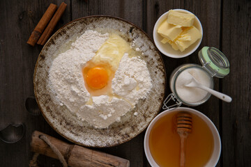 Baking ingredients for baking. There are flour, egg, honey, butter, sugar  on the wooden for baking cookies. Top view.