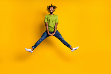 Full length photo portrait of guy jumping up spreading legs isolated on vivid yellow colored background