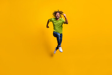 Fototapeta na wymiar Full length photo portrait of man running forward laughing jumping up isolated on vivid yellow colored background