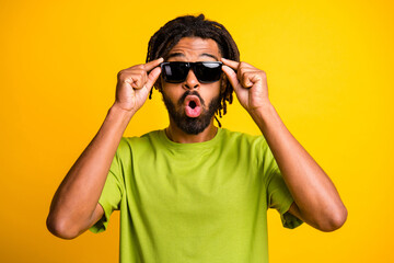 Photo of young african man surprised amazed shocked news rumor hand touch sunglass isolated over yellow color background