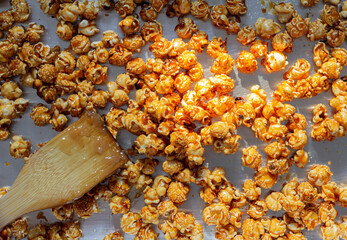 Image flat lay shot of golden caramel popcorn with spoon wooden made from corn in a yellow delicious gourmet crunchy snack food or snack for a homemade or entertaining movie.