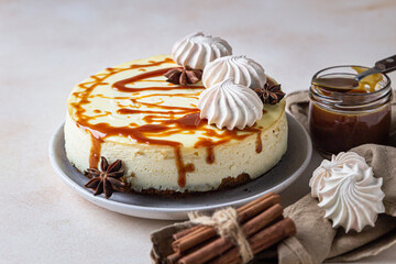 Vanilla cheesecake with carrot cake crust served with salty caramel topping and meringue, light concrete background.