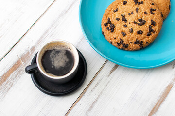A cup of coffee and cookies with chocolate.