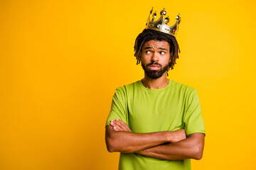 Photo of young handsome man crossed hands wear crown unhappy look empty space wear green t-shirt isolated over yellow color background