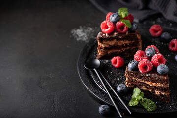slices of homemade chocolate cake with fresh fruit on a black plate