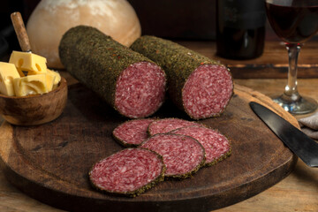 salami, sausages with herbs and cheese cut into slices on wooden board, homemade bread, nuts