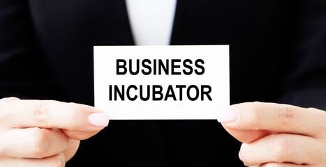 A businessman holds a business card with the text BUSINESS INCUBATOR in front of him.