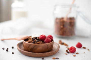 chocolate granola with greek yogurt and raspberries in a wooden bowl