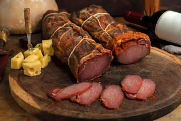 salami, sausages with herbs and cheese cut into slices on wooden board, homemade bread, nuts