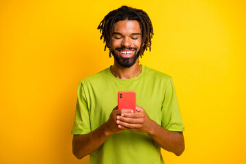 Photo of positive dark skin guy use cellphone read social media news isolated over bright ahine color background