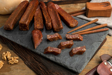 salami, sausages with herbs and cheese cut into slices on wooden board, homemade bread, nuts