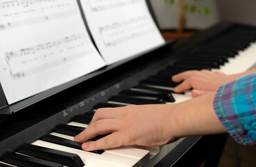Fototapeta na wymiar A child learns to play the piano in distance learning via a laptop over the Internet