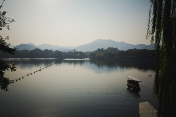 Naklejka na ściany i meble A traditional boat sails across a peaceful lake in China