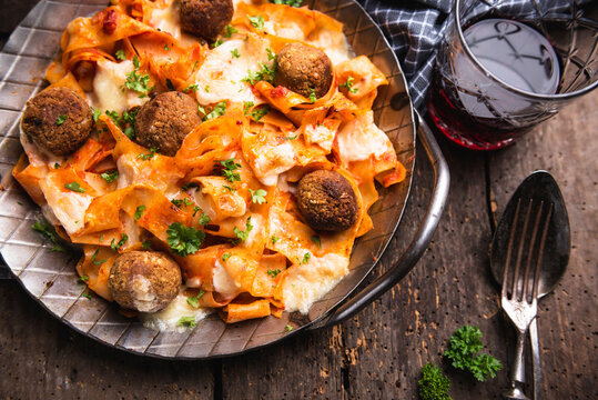 Gratinated tagliatelle with chickpea balls, tomato sauce and almond cheese