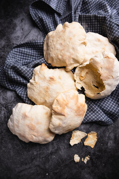 Pita bread on a tea towel, one broken open