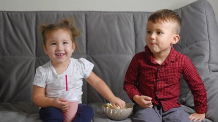 Cute Kids Sitting on the couch feeding each other popcorn very fun