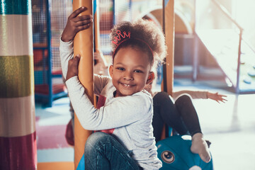 Cute little girl is riding attraction and smiling.