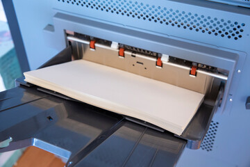 Close-up view of a stack of paper lying on a paper printing machine.