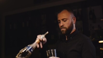 the bearded bartender in a black shirt makes Margarita cocktail