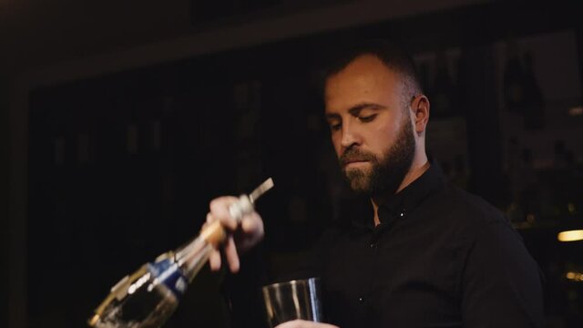 the bearded bartender in a black shirt makes Margarita cocktail