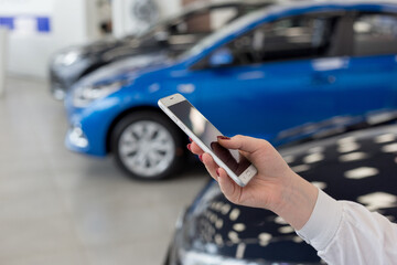 Saleswoman using mobile smart phone at dealer showroom. Modern working process.