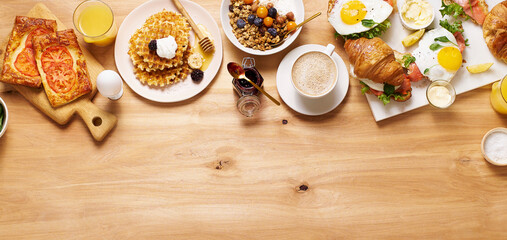 Healthy sunday breakfast with croissants, waffles, granola and sandwiches