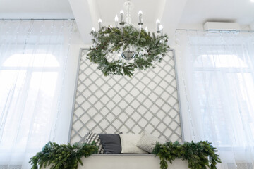 White chandelier with christmas decorations between two big windows