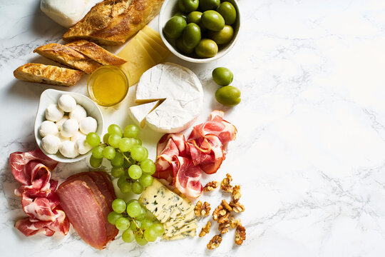 Cheese plate with brie, parmesan, cheddar and meat, fruits and baguette