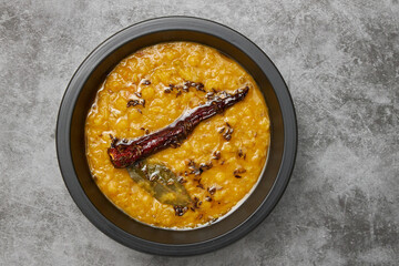 A bowl of lentil tanka dhal on a textured grey background