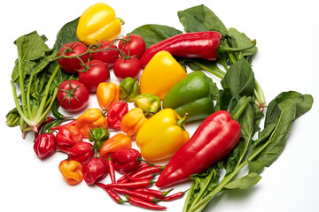 Fresh bell peppers, chillies, tomatoes and greens on white