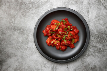 A bowl of Indian red chicken curry on a textured grey background